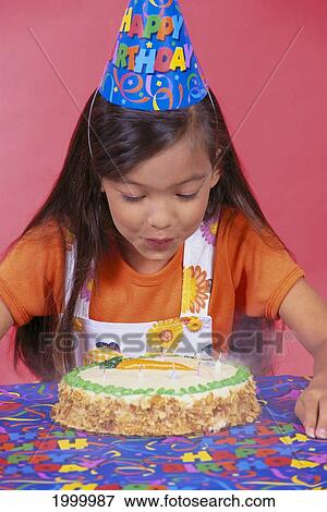 Stock Photo - Birthday Girl Blowing Candles On Cake, Colorful Studio Shot C1166. Fotosearch