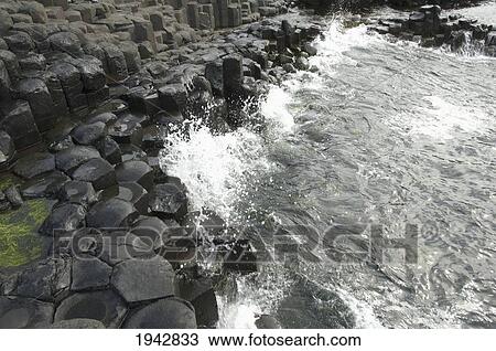 Stock Image - Black Basalt Columns Sticking Out Of The Sea, Giant's Causeway, Northern Ireland, United Kingdom. Fotosearch