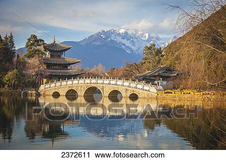 Stock Image - Black Dragon Pool With Jade Dragon Snow Mountain In Background; Lijiang, Yunnan Province, China. Fotosearch