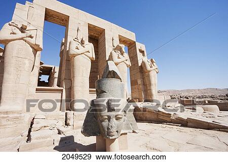 Stock Photo - Black Granite Head Of Ramses Ii And Osirid Pillars Of The Temple Of Ramses Ii At The Ramesseum, Western Thebes, Qina, Egypt. Fotosearch