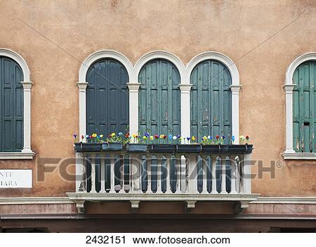 Stock Image - Blossoming flowers decorate the railing of a balcony; Venice, Italy. Fotosearch