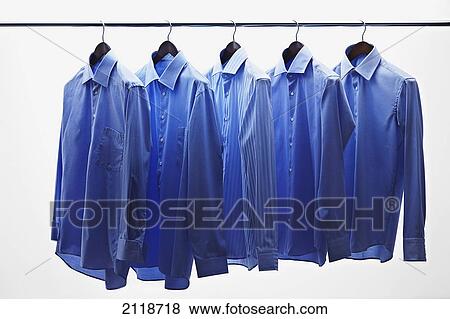 Stock Photo - Blue Dress Shirts Hanging On Clothes Bar Against White Background. Fotosearch