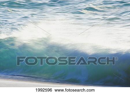 Stock Photograph - Blur Action Of Shoreline Waves Crashing, Afternoon Light Reflections.. Fotosearch