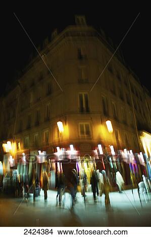Picture - Blur of lights on a building at nighttime and pedestrians walking by; Paris, France. Fotosearch
