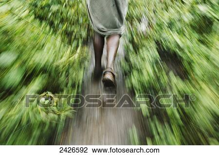 Stock Image - Blur of the motion of a man walking on a path between plants, Omo region, Southwest Ethiopia; Kibish, Ethiopia. Fotosearch
