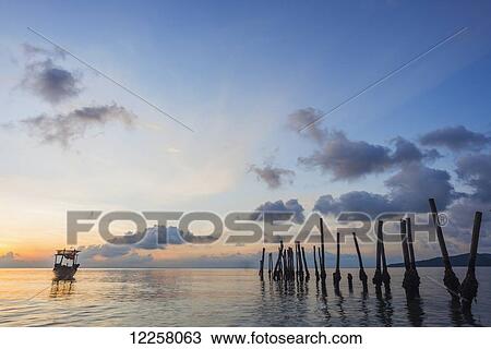 Stock Image - Boat moored at sunset off Tui Beach, Koh Rong Island; Sihanoukville, Cambodia. Fotosearch