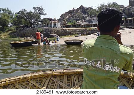 Boatman Wearing 'push & Shove' Shirt In Conical Boat Made Of Bamboo On The Tungabhadra River In Hamp, Karnataka, India View Large Photo Image Stock Image - Boatman Wearing 'push & Shove' Shirt In Conical Boat Made Of Bamboo On The Tungabhadra River In Hamp, Karnataka, India. Fotosearch