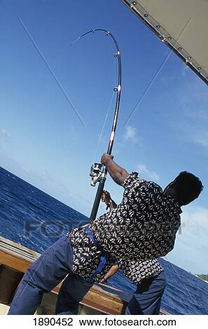 Stock Image - Boatman With Fishing Rod Pulling In Catch. Fotosearch