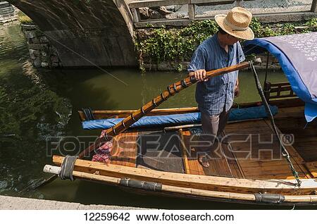 Stock Image - Boatmen drive their boats in water channels, as Venetia; ZhouZhuang, Shanghai, China. Fotosearch