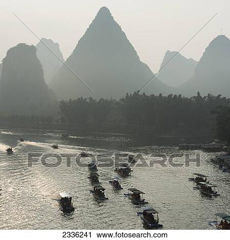 Stock Image - Boats Along The Li River At Sunset; Guilin, Guangxi, China. Fotosearch
