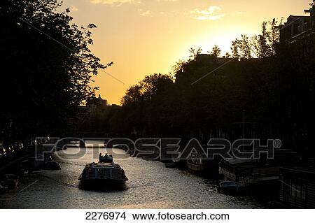 Boats going along canal at dusk; Amsterdam, Holland View Large Photo Image Picture - Boats going along canal at dusk; Amsterdam, Holland. Fotosearch