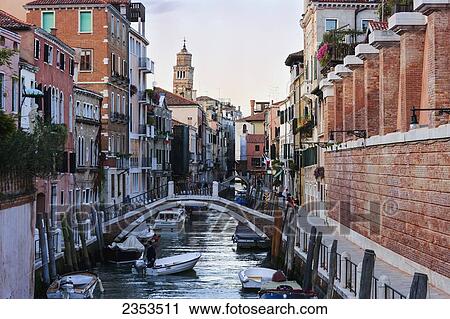 Stock Image - Boats In A Canal And A Bridge Going Over; Venice, Italy. Fotosearch