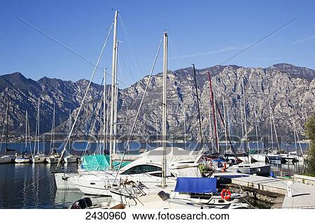 Boats in a harbour with cliffs along Lake Garda; Malcesine, Verona, Italy View Large Photo Image Stock Image - Boats in a harbour with cliffs along Lake Garda; Malcesine, Verona, Italy. Fotosearch