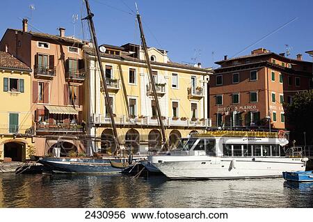 Stock Photograph - Boats in Lake Garda with buildings along the water's edge; Malcesine, Italy. Fotosearch