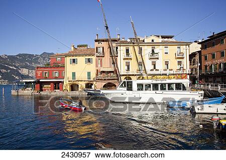 Stock Photo - Boats in the harbour and buildings along the water's edge; Malcesine, Verona, Italy. Fotosearch