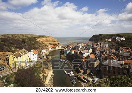 Stock Image - Boats in the river and rooftops; Staithes, North Yorkshire, England. Fotosearch
