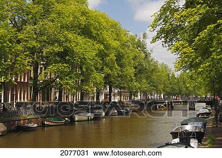 Stock Image - Boats In The Singel Canal; Amsterdam North Holland Netherlands. Fotosearch