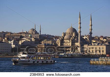 Stock Image - Boats in the water with a view of islamic mosques against a blue sky; Istanbul, Turkey. Fotosearch