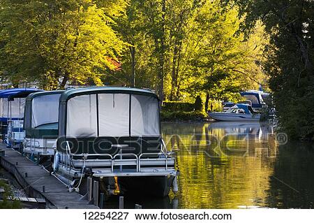 Stock Photo - Boats moored along a wooden dock in autumn; Foster, Quebec, Canada. Fotosearch