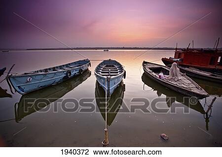 Boats Moored In The Ganges River At Sunset; Varanasi India View Large Photo Image Stock Image - Boats Moored In The Ganges River At Sunset; Varanasi India. Fotosearch