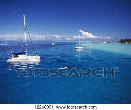 Stock Image - Boats moored off the coast of Tahiti; Tahiti. Fotosearch