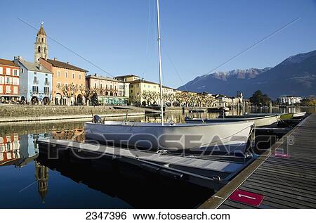 Stock Photograph - Boats Mooring Along Docks In Lake Maggiore With Buildings And The Swiss Alps In The Background; Ascona, Ticino, Switzerland. Fotosearch