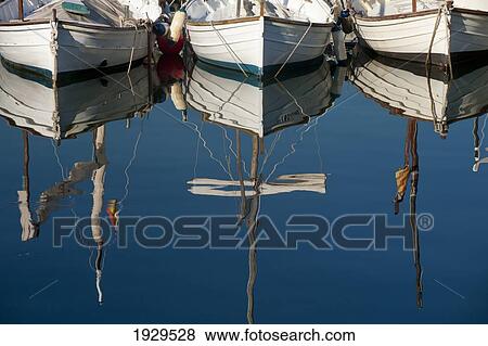 Boats mooring in a harbour with the mirror image in the tranquil water; Majorca, Spain View Large Photo Image Stock Photo - Boats mooring in a harbour with the mirror image in the tranquil water; Majorca, Spain. Fotosearch
