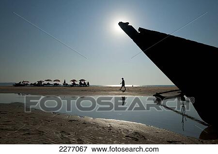 Bow of old boat on beach with people sunbathing in background; Goa, India View Large Photo Image Stock Photo - Bow of old boat on beach with people sunbathing in background; Goa, India. Fotosearch