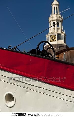 Stock Image - Bow of traditional Dutch barge with the Montelbaanstoren behind; Amsterdam, Holland. Fotosearch