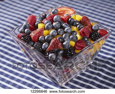 Stock Photograph - Bowl of fresh fruit including blueberries, raspberries, strawberries, blackberries and peaches with a slice of tomato; Ontario, Canada. Fotosearch