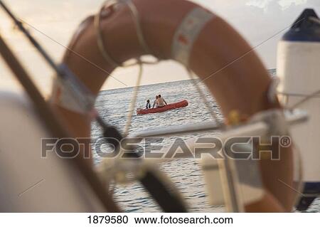 Stock Image - Boy And Men In Boat As Seen Through Life Ring. Fotosearch