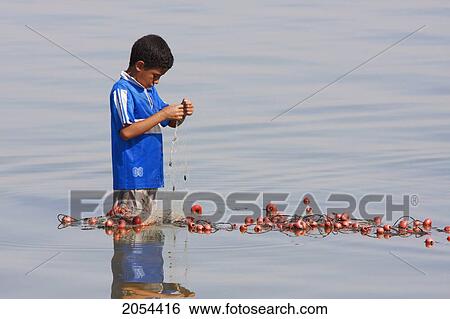 Stock Photograph - Boy Fixing A Fishing Net In Lake Qarun, El Fayoum, Egypt. Fotosearch