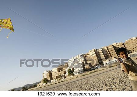 Boy Flying Kite By Walls Of Shibam View Large Photo Image Stock Photo - Boy Flying Kite By Walls Of Shibam. Fotosearch