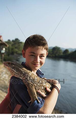 Stock Image - Boy holding a lizard; Thaton, Chiang Rai, Thailand. Fotosearch