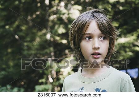 Stock Photo - Boy In T-Shirt Against Green Canopy; Thetford Mines Quebec Canada. Fotosearch