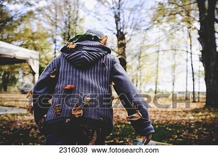 Stock Photo - Boy In Wool Sweater Running Away With Leaves Stuck To His Back; Maricourt Quebec Canada. Fotosearch