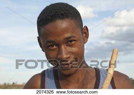Stock Photograph - Boy On A Bridge Over The Maninday River With A Piece Of Sugar Cane, Toliara Province, Madagascar. Fotosearch