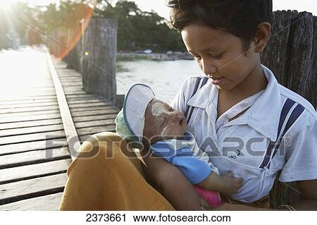 Stock Image - Boy sits with an infant on U Bein Bridge, made of Teak wood; Mandaly, Burma. Fotosearch