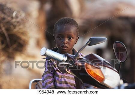 Stock Photo - Boy sitting on a motorcycle in Mopti, Mali. Fotosearch
