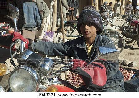 Boy Sitting On A Parked Motorcycle At The Bazaar In Bamiyan, Bamian Province, Afghanistan View Large Photo Image Stock Image - Boy Sitting On A Parked Motorcycle At The Bazaar In Bamiyan, Bamian Province, Afghanistan. Fotosearch