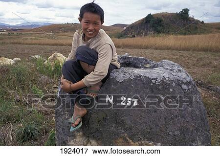 Stock Photo - Boy sitting on rock, Xieng Khuang, Laos. Fotosearch