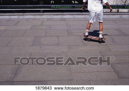 Stock Image - Boy Skateboarding On Pavement. Fotosearch