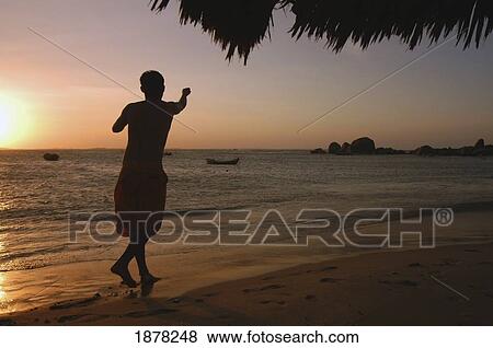 Stock Photo - Boy Walking Along Beach In Silhouette. Fotosearch