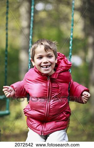 Stock Image - Boy With Missing Tooth, Playing On Swing, Gimli, Manitoba. Fotosearch