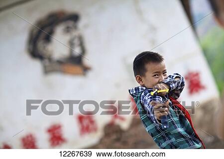 Boy with slingshot in front of Chairman Mao mural; Yunnan, China View Large Photo Image Stock Photo - Boy with slingshot in front of Chairman Mao mural; Yunnan, China. Fotosearch