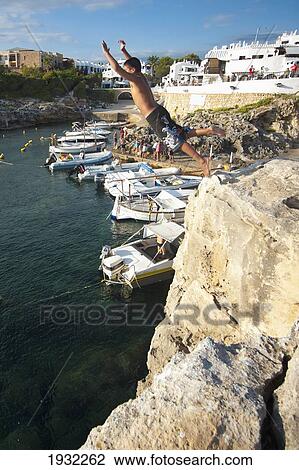 Stock Image - Boys Jumping Into The Sea Near The Village Of Binibequer, Menorca, Balearic Islands, Spain. Fotosearch