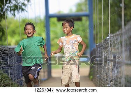 Boys running on a bridge; Battambang, Cambodia View Large Photo Image Stock Photo - Boys running on a bridge; Battambang, Cambodia. Fotosearch