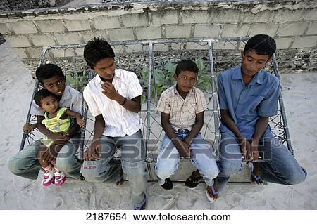 Boys sitting together on a hammock seat; Maldives View Large Photo Image Picture - Boys sitting together on a hammock seat; Maldives. Fotosearch