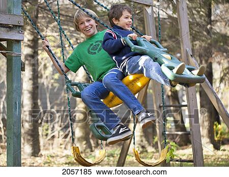 Stock Photography - Boys Swinging On An Outdoor Play Structure. Gimli, Manitoba, Canada.. Fotosearch