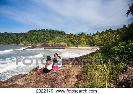 Stock Image - Brazil, Bahia, Itacare, People looking out into ocean on Ribeira beach. Fotosearch